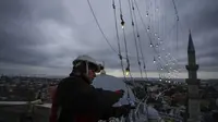 Mahya master Cemil Buyurkan bekerja dalam pemasangan pesan lampu di puncak salah satu menara Masjid Suleymaniye di Istanbul, Turki, Rabu, 6 Maret 2024. (AP Photo/Emrah Gurel)