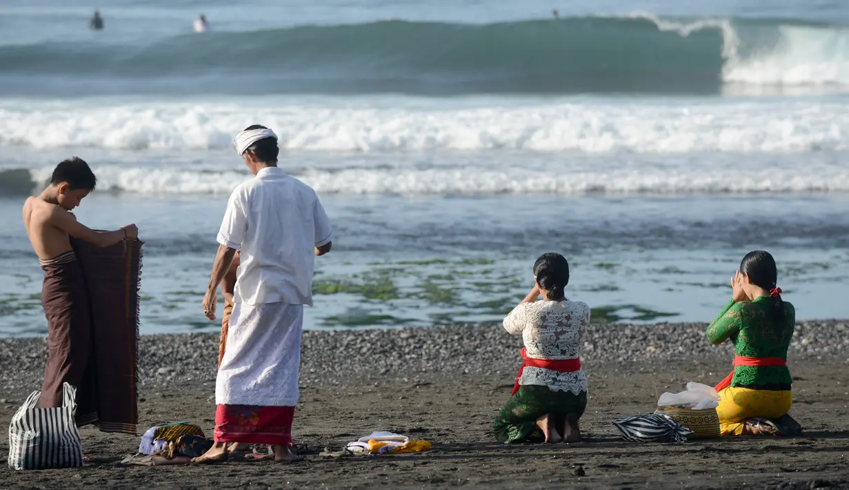 Sebuah keluarga berdoa sebelum menjalani prosesi menyucikan diri saat Hari Banyu Pinaruh di pantai Keramas, Gianyar, Bali, Minggu (12/5/2019). Banyu Pinaruh adalah tradisi Bali yang diadakan sehari setelah merayakan Hari Suci Saraswati untuk membersihkan jiwa dan raga. (SONNY TUMBELAKA/AFP)