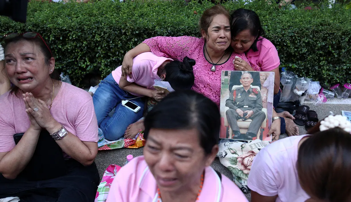 Warga berkumpul di Rumah Sakit Siriraj sambil membawa gambar Raja Thailand Bhumibol Adulyadej di Bangkok, Thailand, Kamis (13/10). Mereka datang karena khawatir akan kondisi kesehatan sang Raja dan berusaha mendoakannya. (REUTERS / Chaiwat Subprasom)