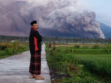 Seorang pria melihat saat Gunung Semeru mengeluarkan material vulkanik saat meletus, Lumajang, Jawa Timur, Indonesia, Minggu (4/12/2022). Gunung Semeru erupsi pada dini hari tadi sekitar pukul 02.46 WIB. (AP Photo)