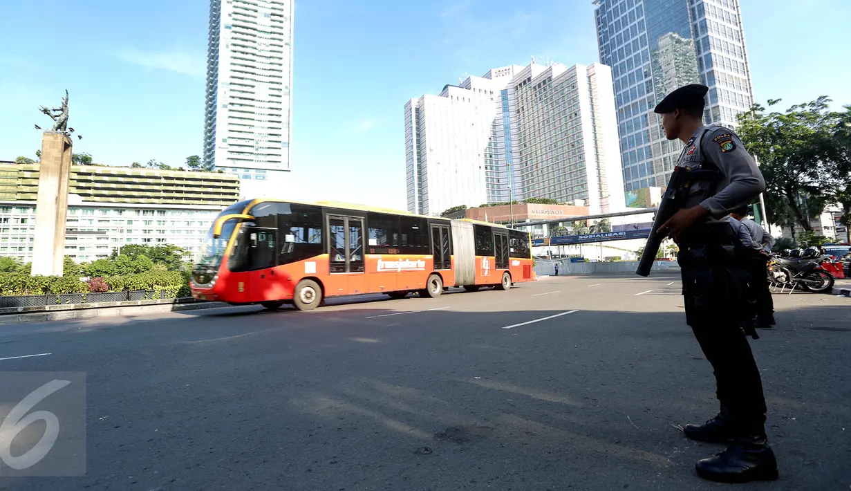Bus Transjakarta melintas saat anggota kepolisian berjaga di kawasan Bundaran HI, Jakarta, Senin (1/5). Ratusan aparat kepolisian dikerahkan melakukan pengamanan demo buruh memperingati May day di sekitaran Bundaran HI. (Liputan6.com/Johan Tallo)