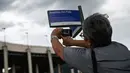 Seorang perempuan mengambil gambar tanda jalan bertuliskan "Avenue King Pele" di luar stadion Maracana di Rio de Janeiro, Brasil pada 4 Januari 2023. Balai Kota Rio de Janeiro secara resmi menamai jalan yang mengelilingi stadion Maracana Avenue Rei Pele (King Pele). (MAURO PIMENTEL/AFP)