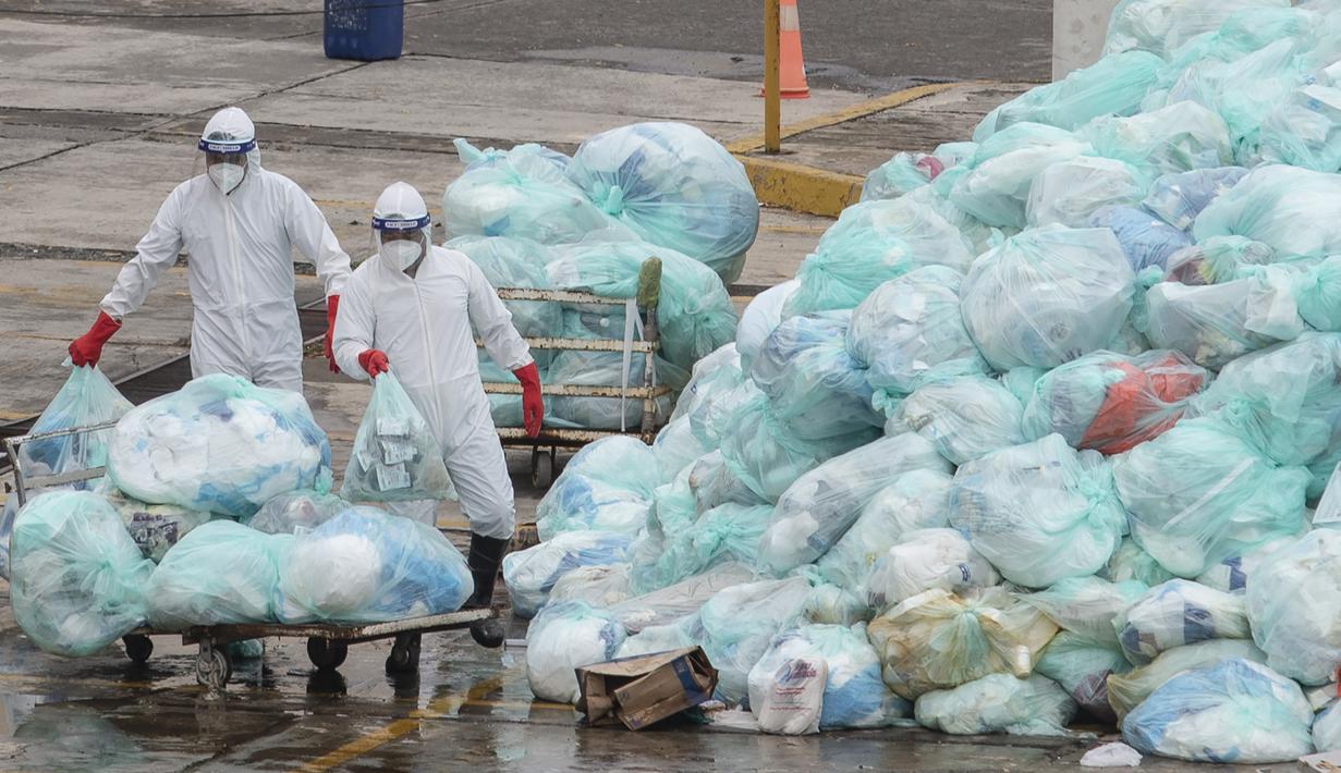 Petugas medis mengenakan alat pelindung diri saat membuang limbah biologis berbahaya di luar Rumah Sakit del Instituto Mexicano del Seguro Social, Veracruz, Meksiko, Rabu (12/8/2020). Pembuangan limbah medis yang tidak tepat menjadi masalah di tengah pandemi COVID-19. (AP Photo/Felix Marquez)