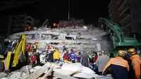Anggota layanan penyelamatan mencari orang-orang yang selamat di puing-puing bangunan yang runtuh di Izmir, Turki, Sabtu (31/10/2020). Gempa bumi yang kuat melanda pada hari Jumat di Laut Aegea antara pantai Turki dan pulau Samos di Yunani, menewaskan beberapa orang. (AP Photo/Emrah Gurel)