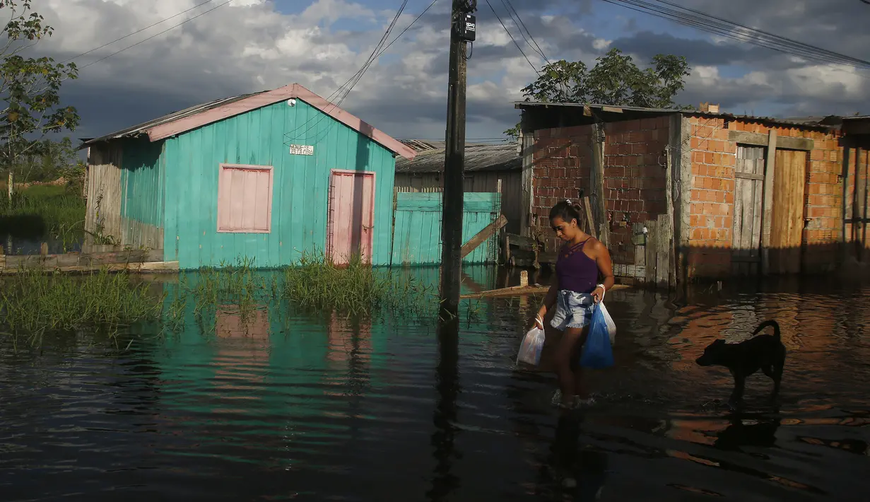 <p>Seorang perempuan berjalan di jalan yang dibanjiri oleh naiknya sungai Negro di Iranduba, negara bagian Amazonas, Brasil, Senin (23/5/2022). Wilayah Amazon sedang dilanda banjir dengan 35 kotamadya yang menghadapi salah satu banjir terburuk mereka dalam beberapa tahun dan permukaan air diperkirakan akan meningkat selama beberapa bulan mendatang. (AP Photo/Edmar Barros)</p>