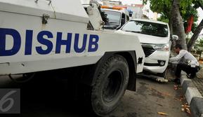 Petugas Dishub DKI saat melakukan penderekan terhadap mobil yang parkir liar di kawasan Pasar Baru, Jakarta, Senin (27/6). Penertiban rutin ini dilakukan untuk membuat efek jera bagi warga yang masih parkir sembarangan. (Liputan6.com/Gempur M Surya)
