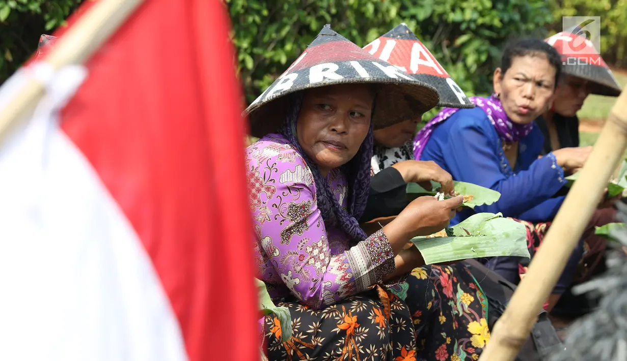 Sejumlah petani Kendeng menyantap makanan saat aksi di depan Istana Negara, Jakarta, Kamis (2/8). Dalam aksinya, mereka melakukan tradisi Brokohan memperingati pertemuan mereka dengan Presiden Jokowi. (Liputan6.com/Helmi Fithriansyah)