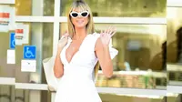 Sering tampil dalam busana colorful, kali ini Heidi tampil dengan warna putih. Ia mengenakan ruffle high low dress berwarna putih dengan mini heels, shoulder bag, dan kacamata warna senada. [Instagram/heidiklum] Penulis: Mufiidaanaiilaa Alifah S.