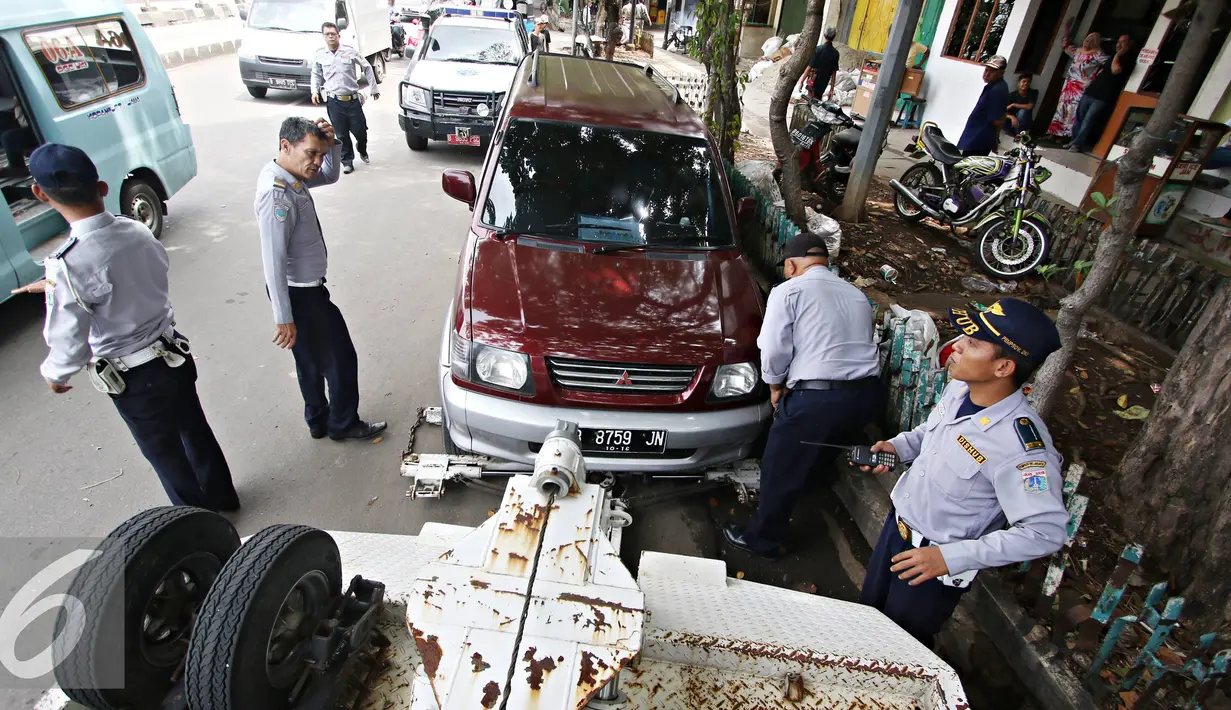 Petugas menderek kendaraan roda empat yang parkir sembarangan di kawasan Jatinegara, Jakarta Timur, Senin (28/12). Meski sudah ditertibkan, pengendara masih tak menghiraukan peraturan tersebut yang mengakibatkan kemacetan. (Liputan6.com/Immanuel Antonius)