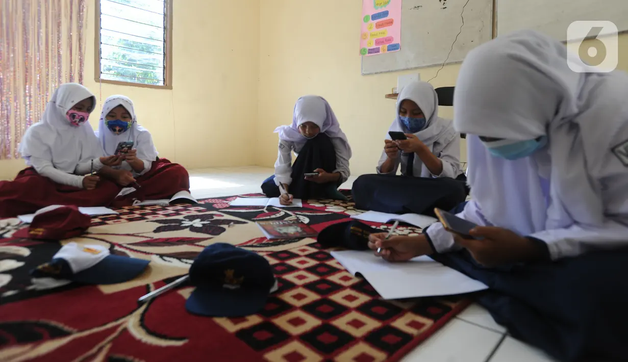 Murid-murid SD dan SMP belajar dengan memanfaatkan wifi gratis di Balai RW kawasan Tegal Gundil, Bogor, Jawa Barat, Senin (21/9/2020). Pemkot Bogor menyebar lebih dari 50 titik wifi publik gratis untuk menunjang Pembelajaran Jarak Jauh (PJJ) siswa di Kota Bogor. (merdeka.com/Arie Basuki)