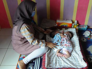 Evi Susanti menjaga putrinya kembarnya, Queenetha Zaina dan Queenesha Zahira di rumahnya di Perumahan Permata Indah Blok W No. 18 RT 18/03, Desa Bojongraharja, Kabupaten Sukabumi, Sabtu (14/08/2021). Bayi kembar siam berusia 1,5 bulan ini memiliki dua jantung dan satu hati. (merdeka.com/Arie Basuki)