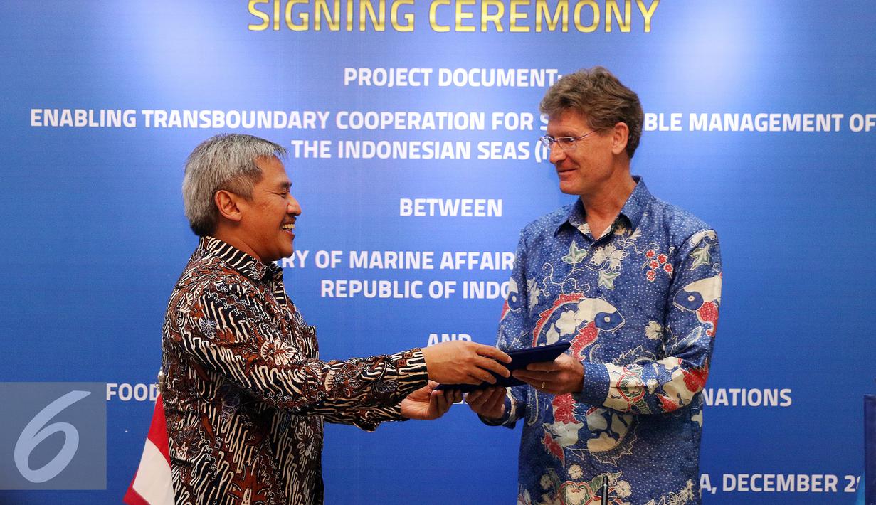 Sekjen KKP, Sjarief Widjaja (kiri) menyerahkan nota kerjasama kepada Kepala Perwakilan FAO untuk Indonesia dan Timor Leste, Mark Smulders usai menandatangani proyek kerjasama di Jakarta, Rabu (28/12). (Liputan6.com/Helmi Fithriansyah)