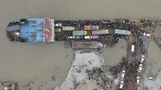 Foto udara yang diambil pada 27 Juni 2021 ini memperlihatkan penumpang naik kapal feri jelang pengetatan lockdown, Munshiganj, Bangladesh. Ribuan pekerja migran meninggalkan Ibu Kota Bangladesh, Dhaka, jelang lockdown yang diperketat. (Munir Uz zaman/AFP)