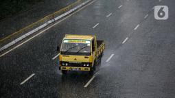 Sebuah truk melintas di tengah hujan lebat di kawasan Jalan Sudirman, Jakarta, Selasa (29/6/2021). BMKG mengungkapkan wilayah Jakarta dan sekitarnya masih dilanda hujan dan hawa dingin di musim kemarau. (Liputan6.com/Faizal Fanani)