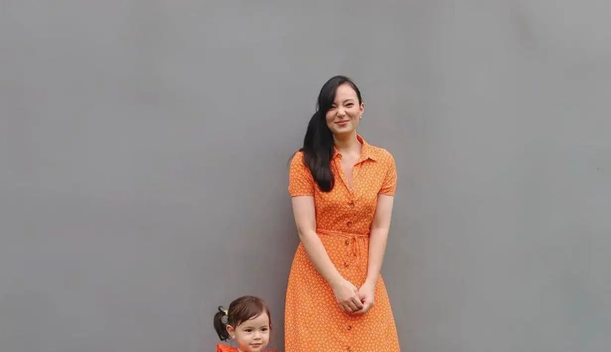 Kompak serba orange bareng Chloe, istri Jonas Rivanno ini memilih polkadot shirt dress lengan pendek dengan detail kancing di bagian depan. Sementara putrinya mengenakan sleeveless ruffle neck dress warna senada.  (Instagram/asmirandah89).