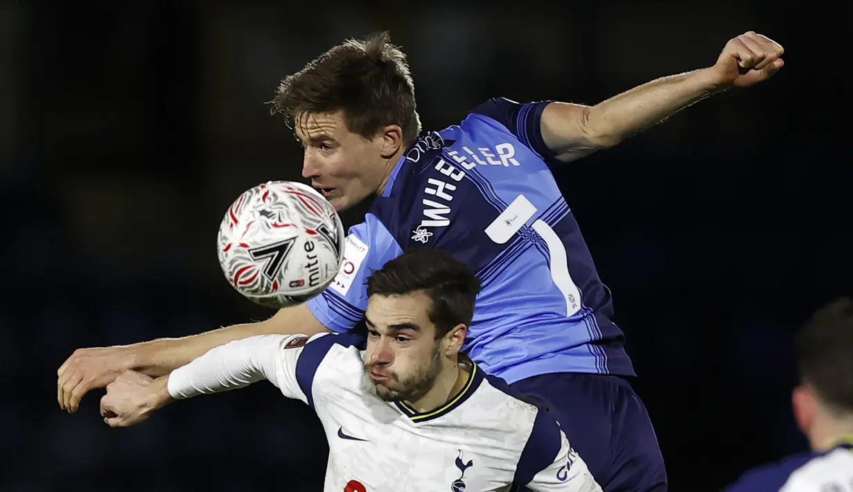 Gelandang Wycombe Wanderers, David Wheeler (atas) berduel udara dengan gelandang Tottenham Hotspur, Harry Winks dalam laga babak keempat Piala FA 2020/21 di Adams Park Stadium, Senin (25/1/2021). Wycombe Wanderers kalah 1-4 dari Tottenham Hotspur. (AFP/Adrian Dennis)