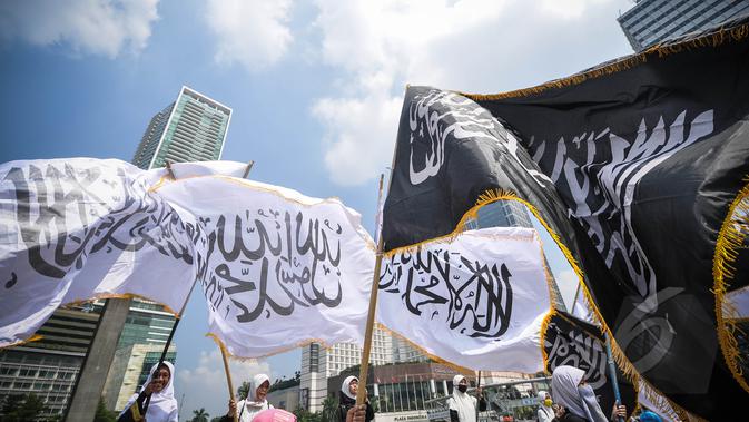 Aktivis Perempuan HTI mengibarkan bendera HTI saat melakukan aksi di Bundaran HI, Jakarta, Minggu (22/3/2015). Mereka menolak sistem neoliberalisme dan neoimperialisme yang digunakan oleh Indonesia.(Liputan6.com/Faizal Fanani)