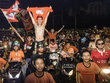 Suporter Persija Jakarta, The Jakmania, bergembira saat merayakan pesta juara Liga 1 di Bundaran Hotel Indonesia, Jakarta, Minggu (9/12). Persija unggul satu poin dari PSM Makassar di puncak klasemen. (Bola.com/Vitalis Yogi Trisna)