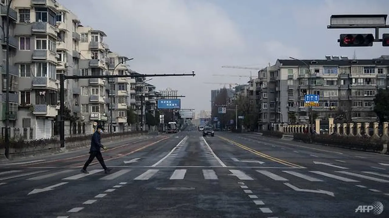 Seorang lelaki yang mengenakan masker pelindung berjalan di jalan kosong di Hangzhou, China, pada 5 Februari 2020.