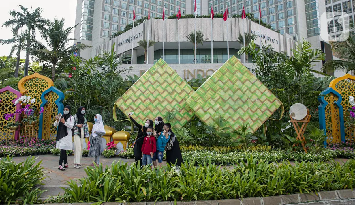 <p>Sejumlah warga berfoto dengan dekorasi bertemakan Idul Fitri di kawasan Bundaran HI, Jakarta, Rabu (27/4/2022). Dekorasi berbentuk masjid, ketupat, dan bedug yang dihiasi oleh tanaman tersebut dalam rangka menyambut Idul Fitri 1443 Hijriah. (Liputan6.com/Faizal Fanani)</p>