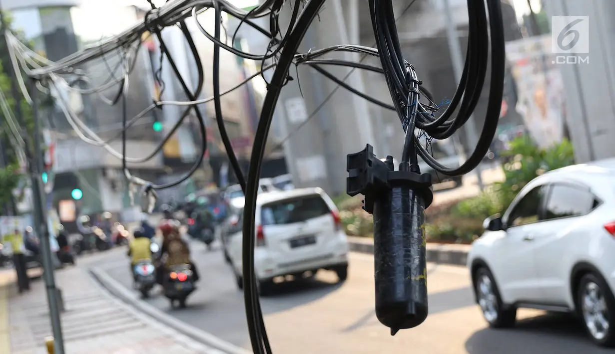 Instalasi kabel menjuntai ke trotoar di Jalan Kyai Maja, Jakarta, Rabu (10/4). Selain menganggu kenyamanan pejalan kaki, kondisi instalasi kabel yang semrawut tersebut juga berbahaya apabila mengandung aliran listrik. (Liputan6.com/Immanuel Antonius)