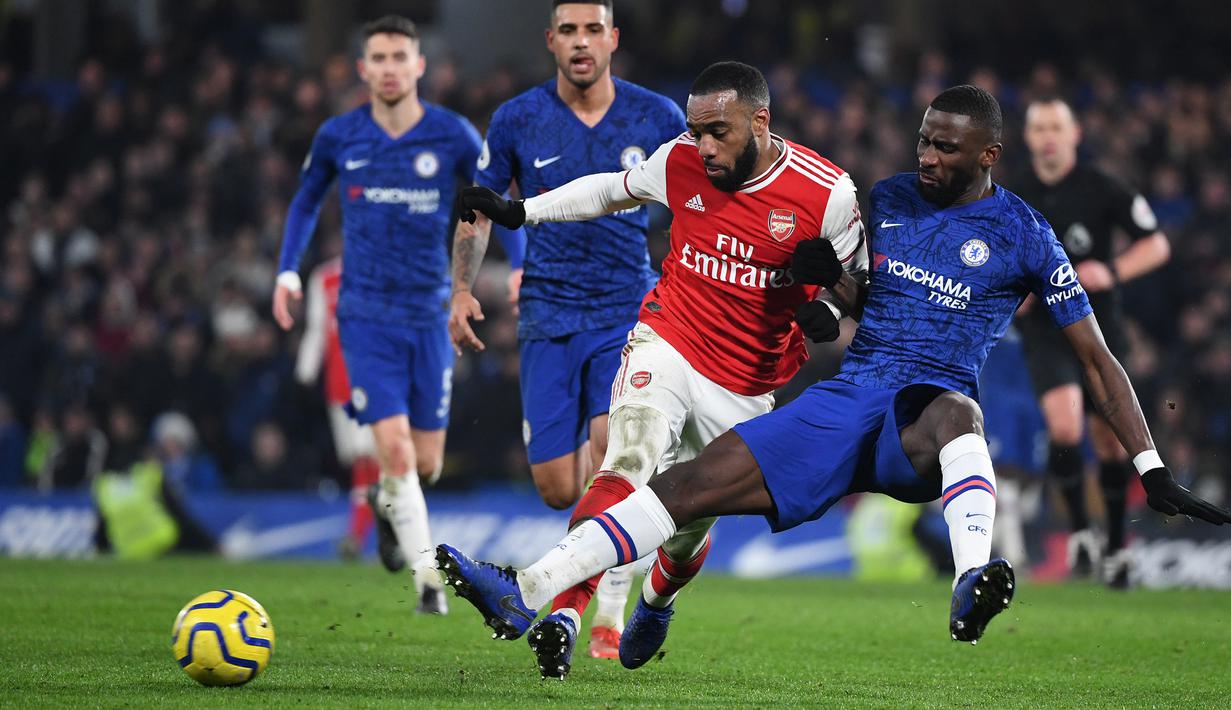 Striker Arsenal, Alexandre Lacazette, berebut bola dengan bek Chelsea, Antonio Rudiger, pada laga Premier League pekan ke-24 di Stamford Bridge, London, Rabu (22/1). Arsenal tahan imbang Chelsea 2-2. (AFP/Daniel Leal-Olivas)
