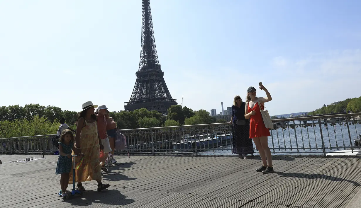 Turis berfoto dengan latar belakang dekat Menara Eiffel di Paris, Rabu (31/8/2022). Pariwisata kembali dengan sepenuh hati ke Prancis musim panas ini, mengirimkan pendapatan melebihi tingkat pra-pandemi menurut data pemerintah yang dirilis minggu ini. (AP Photo/Aurelien Morissard)
