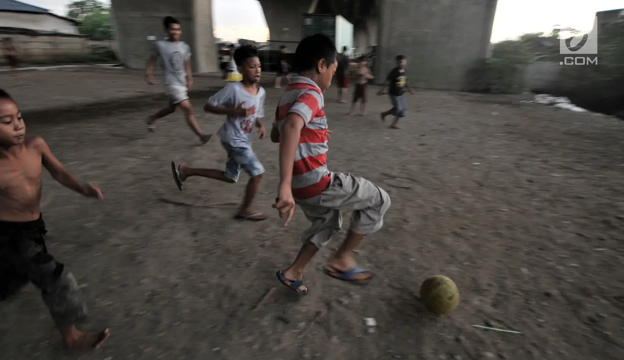 Anak-anak bermain sepak bola di kolong jalan Tol Lingkar Utara, Kalibaru, Cilincing, Jakarta, Kamis (28/3). Lahan di kolong jalan tol tersebut rencananya oleh Pemkot Jakarta Utara akan disulap menjadi ruang terbuka hijau bernama Taman Maju Bersama (TMB). (merdeka.com/Iqbal S Nugroho)