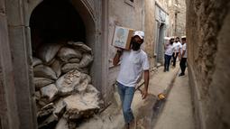 Para relawan Irak di asosiasi lokal saat mendistribusikan jatah makanan ke rumah tangga selama bulan Muslim Ramadhan di kota Mosul utara (7/5/2021). (AFP Photo/Zaid AL-Obeidi)