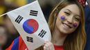 Seorang wanita cantik pendukung Korea Selatan mengibarkan bendera Korsel saat tim kesayangannya berlaga melawan Aljazair di Porto Alegre pada 22 Juni 2014 (AFP PHOTO/PHILIPPE DESMAZES)