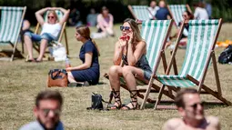 Sejumlah warga Inggris bersantai di atas kursi sambil menikmati sinar matahari di Green Park, London, Senin (25/6). Pada Juli 2018, suhu di ibu kota London tercatat 29.1 derajat Celcius dan diprediksi akan mencapai 30 derajat Celcius. (AFP/Tolga Akmen)