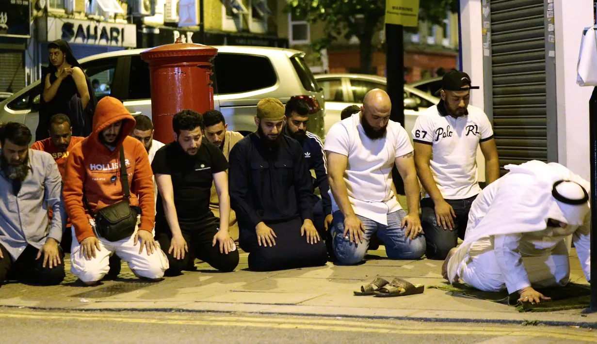 Umat muslim melaksanakan salat di lokasi sebuah van yang menabrak pejalan kaki di Finsbury Park Road, London utara, Senin (19/6). Mereka menggelar salat di pinggir jalan untuk mendoakan para korban insiden penabrakan. (Yui Mok/PA via AP)