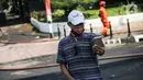 Seorang pria berswafoto dengan latar belakang gedung utama Kejaksaan Agung RI yang terbakar di Jalan Sultan Hasanuddin, Jakarta, Minggu (23/8/2020). Banyak warga yang memadati Jalan Hasanuddin untuk melihat langsung kondisi gedung Kejaksaan Agung yang hangus dilalap api. (Liputan6.com/Faizal Fanani)
