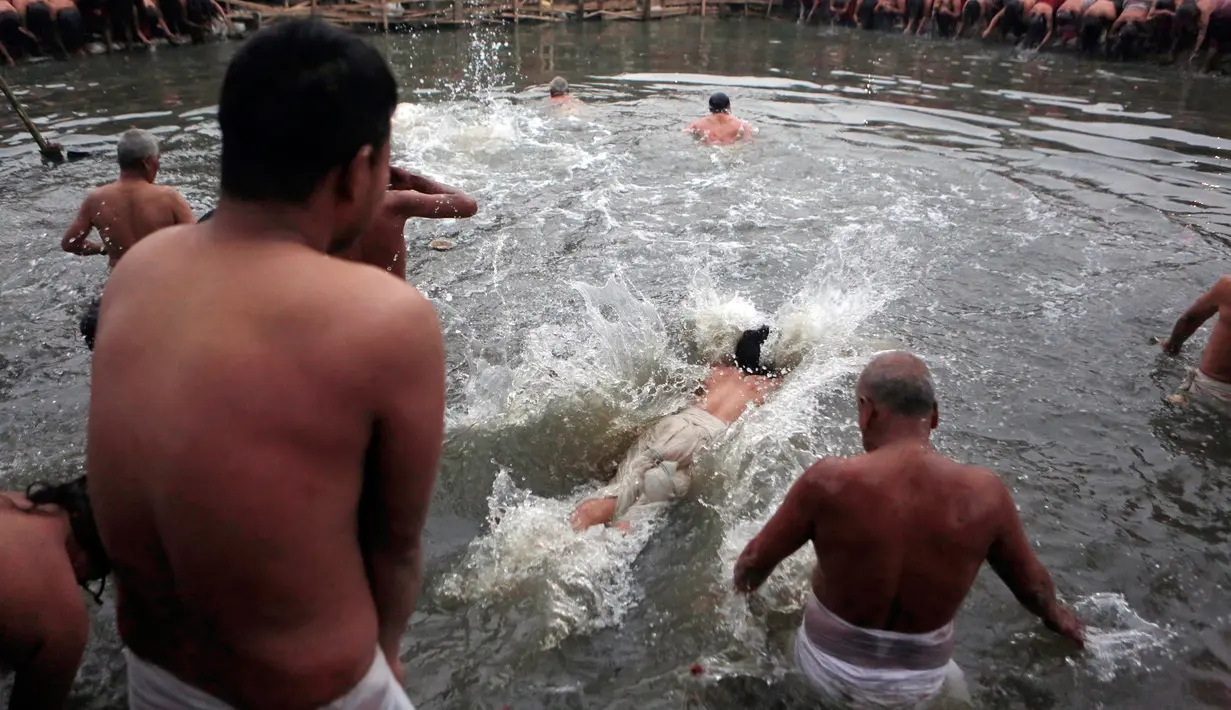Umat Hindu Nepal menceburkan ke air untuk penyucian diri saat hari terakhir festival Madhav Narayan di Bhaktapur, Nepal (31/1). Sebelum hari ritual ini, mereka melakukan puasa sebulan penuh. (AP Photo / Niranjan Shrestha)
