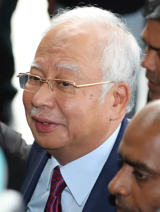 Mantan Perdana Menteri Malaysia, Najib Razak tiba untuk menjalani sidang dakwaan di Pengadilan Kuala Lumpur, Rabu (4/7). Najib sempat tersenyum saat berjalan sambil dikawal petugasKomisi Anti-Korupsi Malaysia (MACC). (AP/Vincent Thian)
