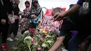 Pengunjung car free day meletakan bunga yang diberikan oleh anggota TKN Milenial Jokowi-Ma'ruf dalam kegiatan tabur bunga di Bundaran HI, Jakarta, Minggu (28/4/2019). Aksi tersebut sebagai bentuk duka atas meninggalnya 272 petugas KPPS dalam Pemilu 2019. (Liputan6.com/Faizal Fanani)