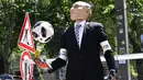 Aktivis mengenakan topeng Presiden Rusia Vladimir Putin menangkap bola selama protes di depan kedutaan Rusia menjelang dimulainya Piala Dunia Sepak Bola 2018 di Berlin, Jerman (12/6). (AFP Photo/Tobias Schwarz)