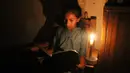 Seorang gadis membaca dengan bantuan lilin di tengah pemadaman listrik di Kolombo, Sri Lanka (17/8/2020). Sri Lanka mengalami pemadaman listrik berskala nasional pada Senin (17/8) karena kerusakan teknis di sebuah pembangkit listrik di Kerawalapitiya. (Xinhua/A. Hapuarachchi)