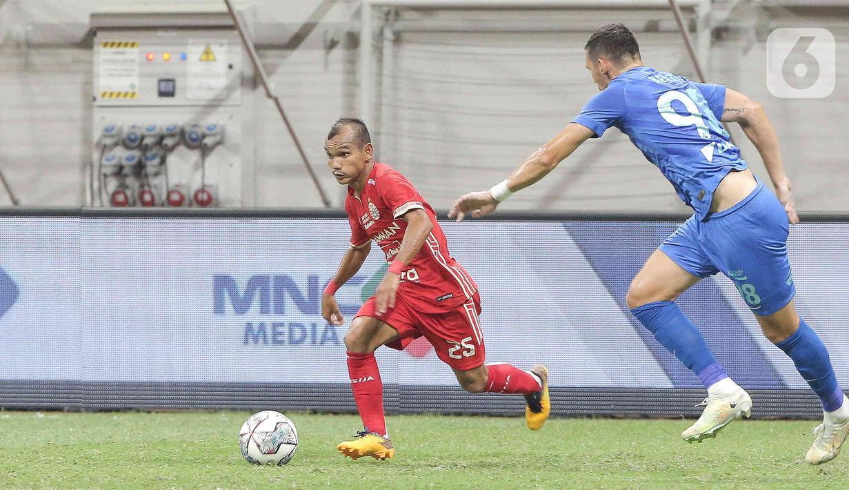 Pesepak bola Persija Jakarta Riko Simanjuntak (kiri) berusaha melewati pesepak bola Chonburi FC pada laga persahabatan dalam rangka peresmian Stadion Jakarta International Stadium (JIS) di Jakarta, Minggu (24/7/2022). Pertandingan berakhir imbang dengan skor 3-3. (Liputan6.com/Herman Zakharia)