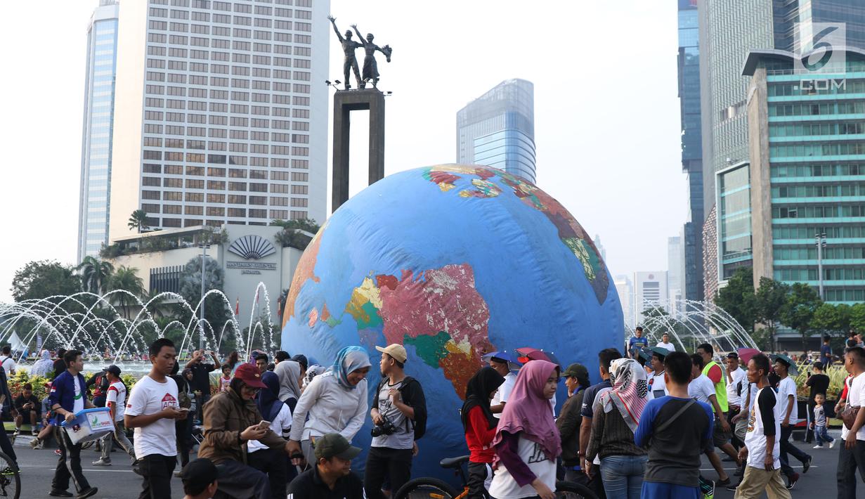 Replika bola dunia berukuran besar digelindingkan di sekitar kawasan Bundaran HI, Jakarta, Minggu (16/9). Acara ini bagian dari peringatan Hari Ozon Sedunia 2018 dengan tema Keep Cool and Carry on! The Montreal Protocol. (Liputan6.com/Helmi Fithriansyah)