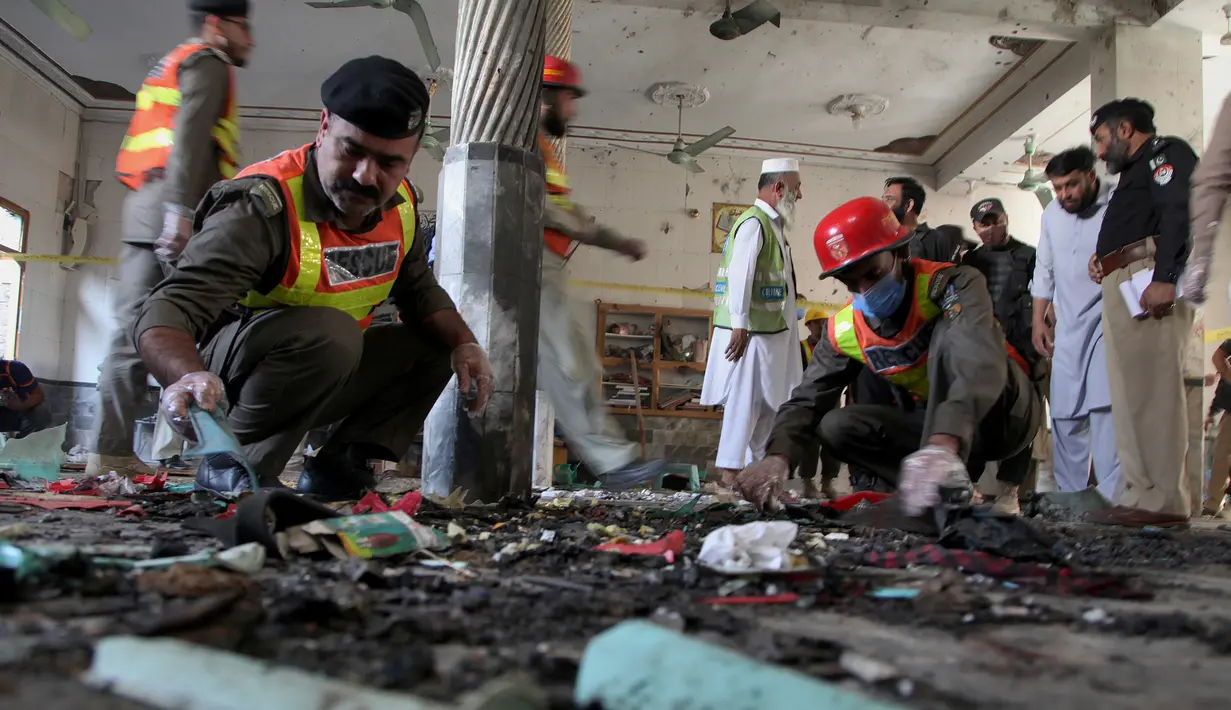 Petugas penyelamat dan aparat kepolisian memeriksa lokasi ledakan bom di sebuah madrasah di kota Peshawar, Pakistan, Selasa (27/10/2020). Ledakan di salah satu sekolah agama tersebut menewaskan sedikitnya tujuh orang, termasuk anak-anak, dan melukai puluhan lainnya. (AP Photo/Muhammad Sajjad)