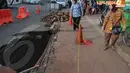 Dua orang wanita pejalan kaki tampak penasaran terhadap jalan yang amblas di kawasan Sudirman . Kamis (10/4/2014)  (Liputan6.com/Johan Tallo).