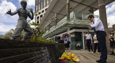 Para penggemar berkumpul di depan patung seniman bela diri Bruce Lee untuk memperingati 50 tahun kematiannya di Hong Kong, Kamis, 20 Juli 2023. (AP Photo/Louise Delmotte)