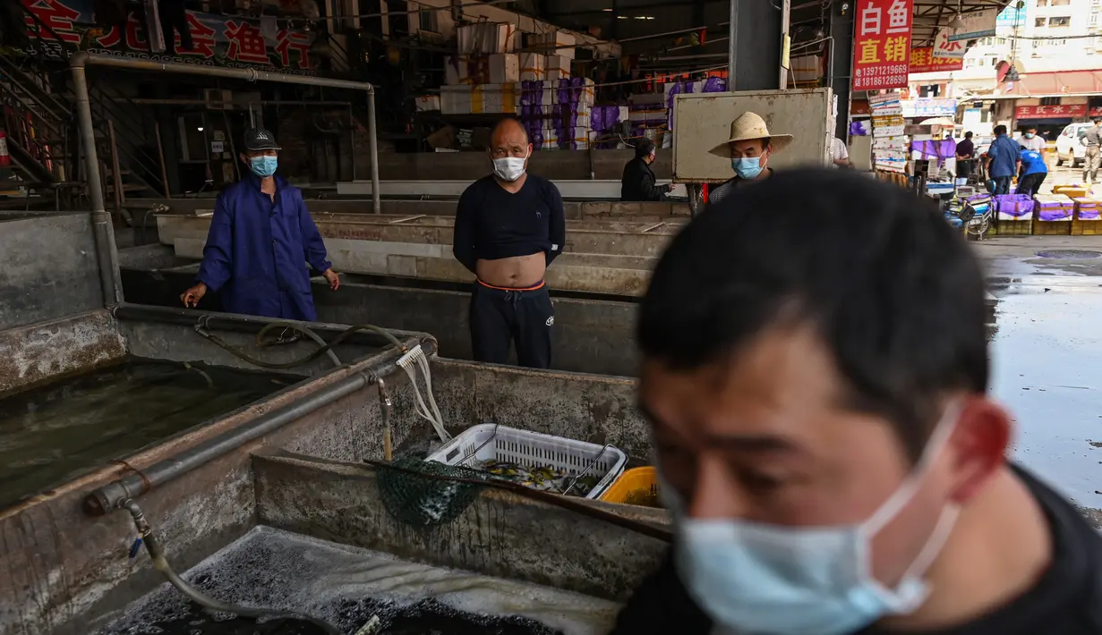 Para pedagang mengenakan masker saat berjualan di Pasar Baishazhou Wuhan di Wuhan, provinsi Hubei, Rabu (15/4/2020). Lebih dari 90 persen kios pasar basah di Wuhan telah kembali buka sejak pemerintah mencabut aturan lockdown di wilayah pusat pandemi corona tersebut. (Hector RETAMAL/AFP)