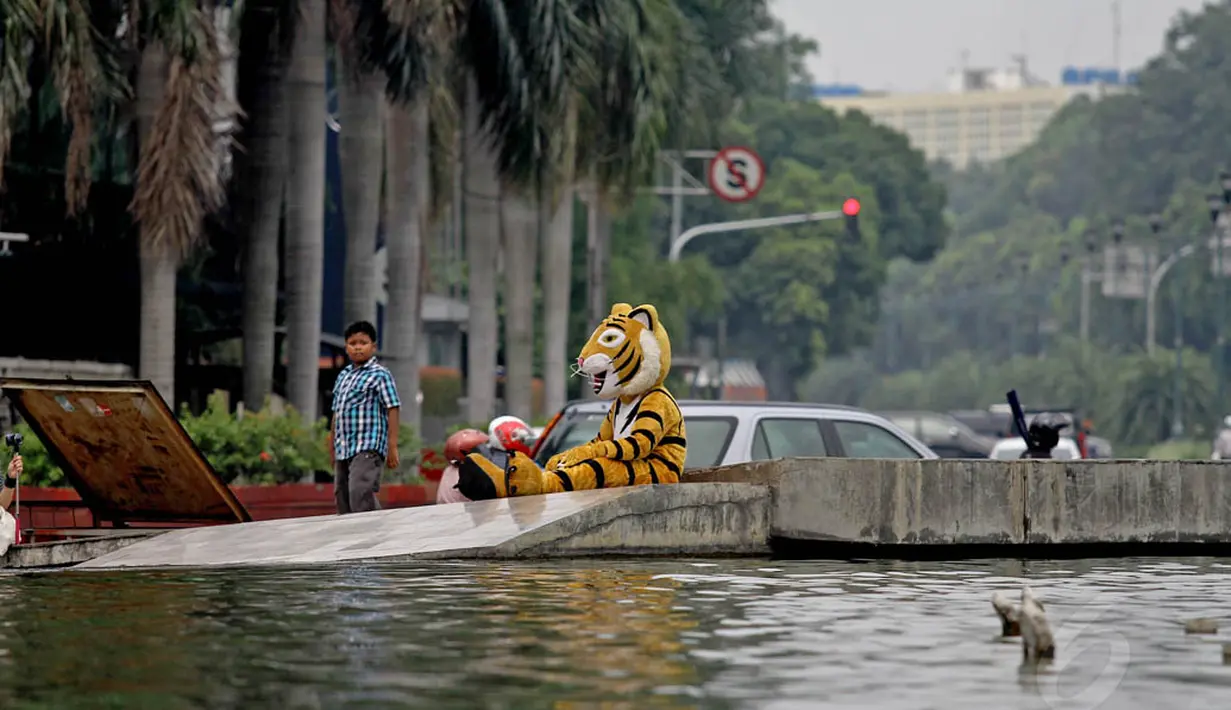 Aktivis Greenpeace berkostum harimau tampak tengah duduk beristirahat di pinggir kolam Bundaran HI, Jakarta, Minggu (11/5/14). (Liputan6.com/Faizal Fanani)