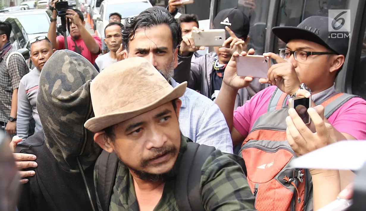Axel Matthew Thomas didampingi ayahnya, Jeremy Thomas saat tiba di Polda Metro Jaya, Jakarta, Rabu (19/07). Axel Matthew Thomas, resmi ditetapkan sebagai tersangka oleh Polda Metro Jaya usai memesan happy five. (Liputan6.com/Herman Zakharia)