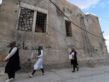 Sejulmah wanita dari Relawan Irak di asosiasi lokal saat mendistribusikan jatah makanan ke rumah tangga selama bulan Muslim Ramadhan di kota Mosul utara (7/5/2021). (AFP Photo/Zaid AL-Obeidi)