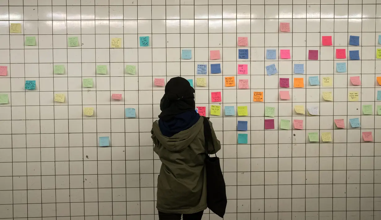 Seorang wanita menempelkan post-it sebagai bagian dari 'subway therapy' di dinding stasiun Union Square, New York, Kamis (10/11). Subway therapy digunakan kaum komuter yang kesal dan kecewa terpilihnya Donald Trump sebagai Presiden AS. (DREW ANGERER/AFP)