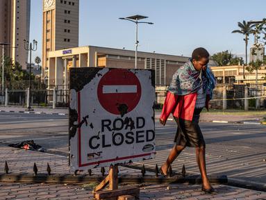 Seorang wanita menutupi wajahnya ketika sisa-sisa gas air mata terasa di udara saat berjalan melewati gedung Parlemen Kenya di pusat kota Nairobi, pada 26 Juni 2024. (LUIS TATO/AFP)