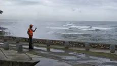 Seorang pria mengambil foto dengan ponselnya saat ombak akibat Badai Tropis Franklin pecah di tembok laut di Santo Domingo, Republik Dominika, Selasa, 22 Agustus 2023. (AP Photo/Ricardo Hernandez)